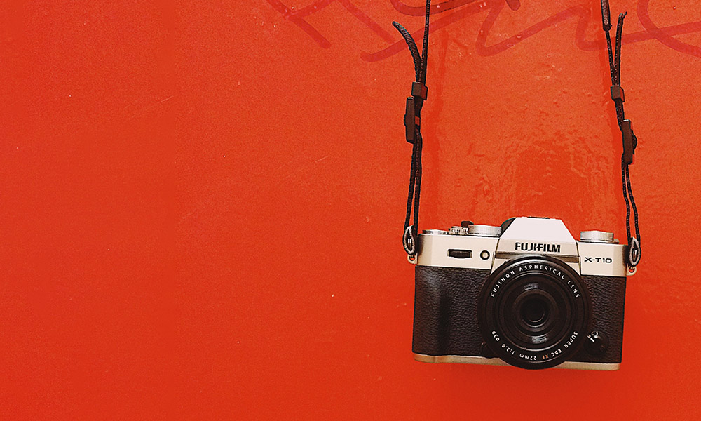 A camera hanging in front of a bright red wall.
