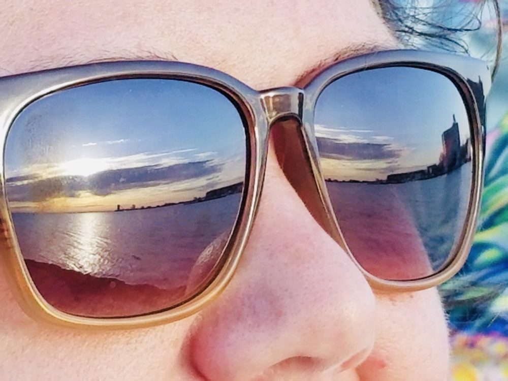 Skyline at sunset reflected in a person's sunglasses.