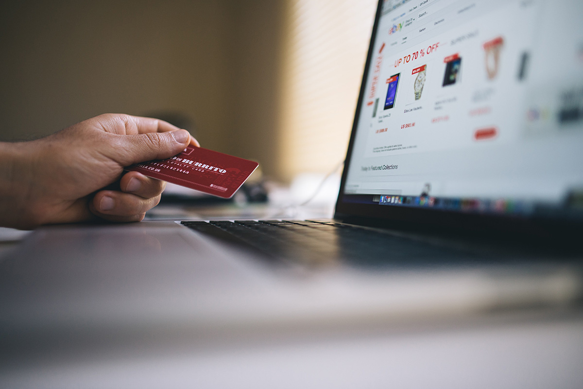 Person holding a credit card while browsing an e-commerce website.