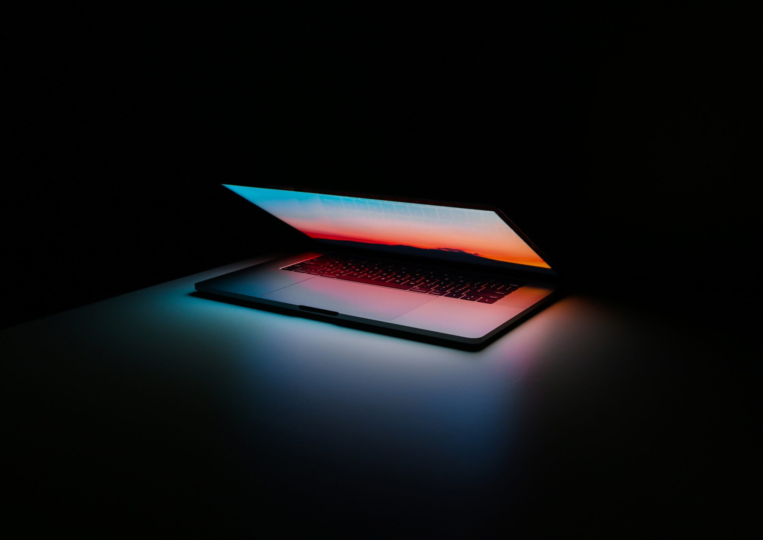 A partially-closed laptop with a gradient background.
