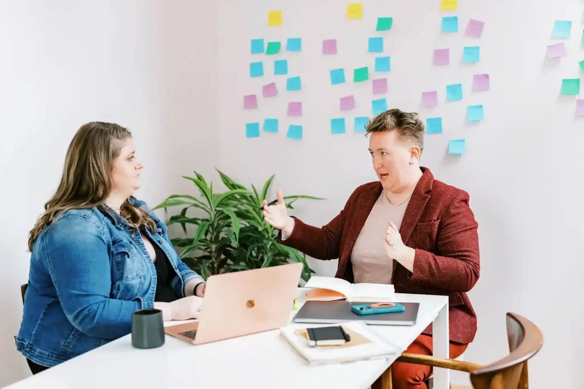 RedTree team members having a discussion in an office in front of a wall covered in colorful Post-It Notes.